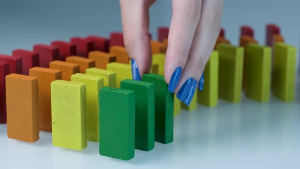 Line up of Dominoes in Rainbow Falling Colors with LGBT Colors of a Hand