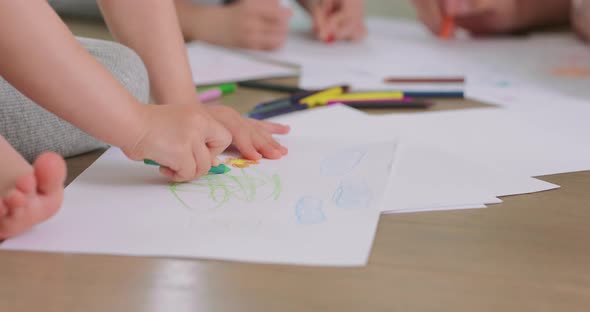 Close Up of a a Little Girl's Hands Who is Drawing with Pencils on the White Paper on the Floor