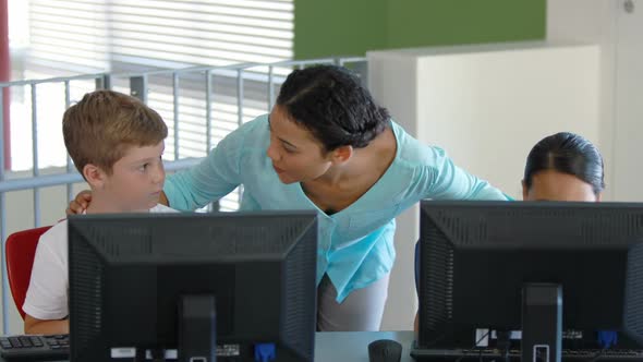 Teacher assisting schoolgirls in learning computer