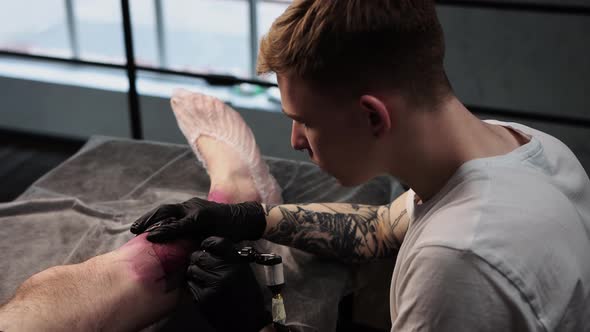 Tattoo Session in Salon  Client Lying on the Couch and Getting a Big Tattoo on His Leg