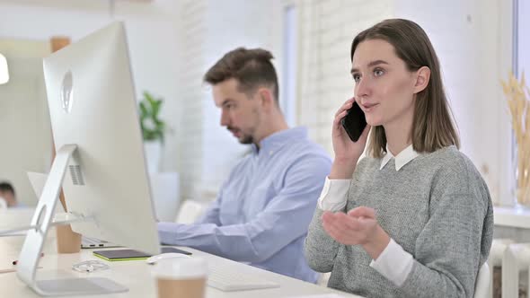 Happy Creative Woman Talking on Smart Phone in Office