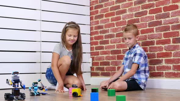 Sevenyearold Boy and Girl Play Electronic Robots Cars Modern Toys on the Radio Control