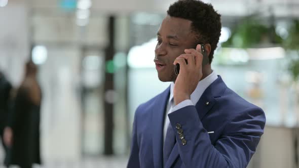 African Businessman Talking on Smartphone in Modern Office