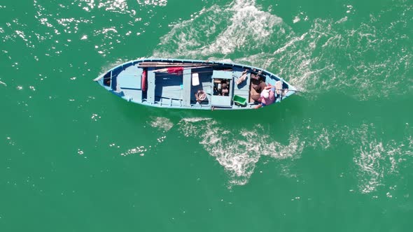 Top down view of wooden fishing boat and fisherman, sailing. alt