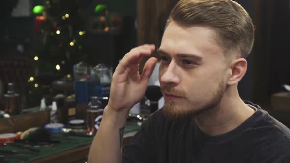 Handsome Bearded Man Examining His New Haircut at the Barbershop