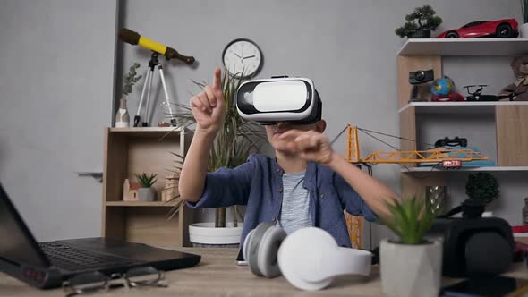 Modern Teen Boy in Virtual Reality Headset which Playing Video Game at Home