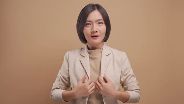 Happy asian business woman adjusting her suit and looking at camera like a mirror isolated