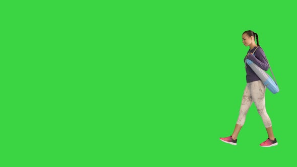 Sporty Girl Wearing Leggings Holding Rolled Up Yoga Mat and Walking By on a Green Screen Chroma Key