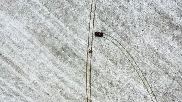 Top down view of a ATV riding in a Snowy Field - Aerial View