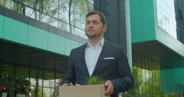 Businessman in Despair Lost Job and Walking Near Office Center with Carton Box and Documents with a