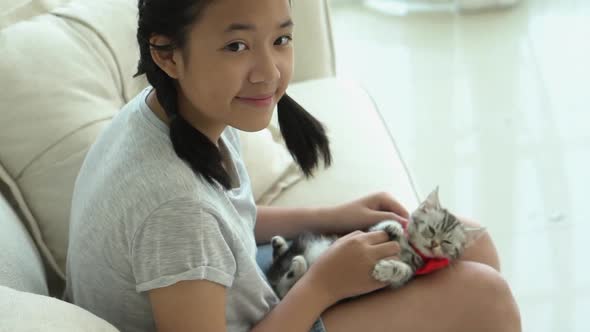 Beautiful Asian Girl Playing With Kitten On Sofa At Home Slow Motion