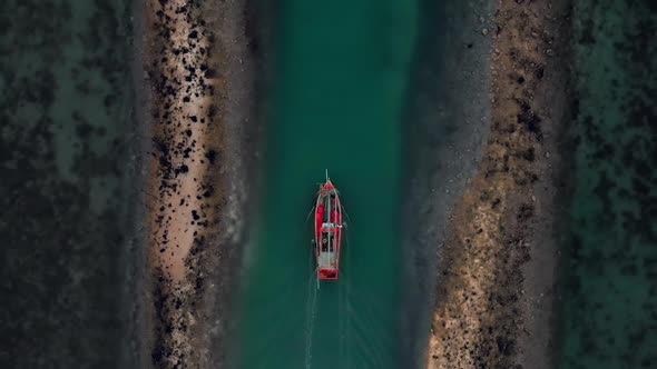 Aerial flight up follow above fisherman boat goes from dock among coral reefs