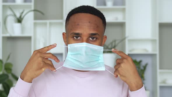 Portrait of African American Man Putting on Medical Mask Before Going Out As Protection Respirator