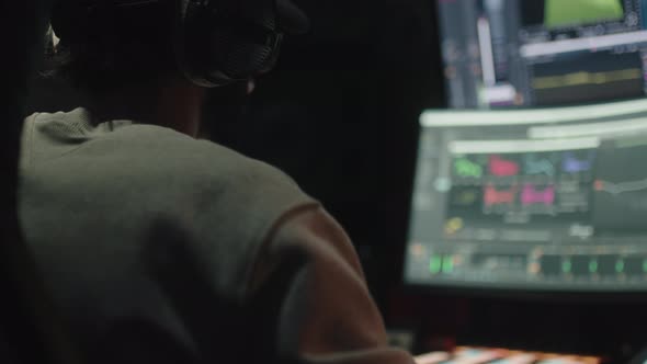 Sound Engineer Seen Seated From Behind Uses the Computer to Mix Audio Music