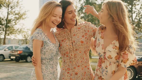 Three young beautiful girls posing outdoors at summer sunny day