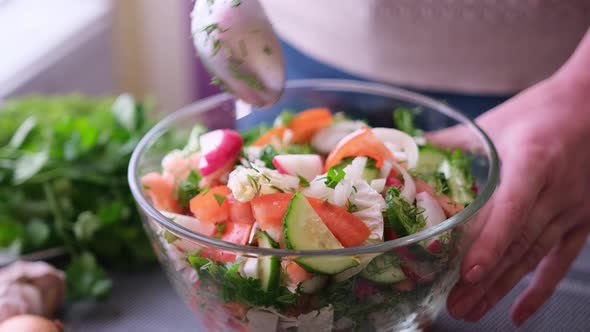 Woman Mixes a Salad of Vegetables in Glass Bowl  Tomatoes Cucumbers Onion Parsley