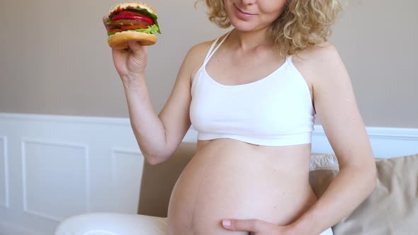 Hungry Pregnant Woman Holding Vegan Hamburger Relaxing At Home