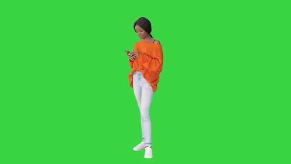 A Beautiful Young Woman Using Her Phone on a Green Screen, Chroma Key.