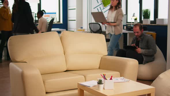 Employee Holding Laptop Sitting in Relax Zone on Confortable Couch Typing on Pc