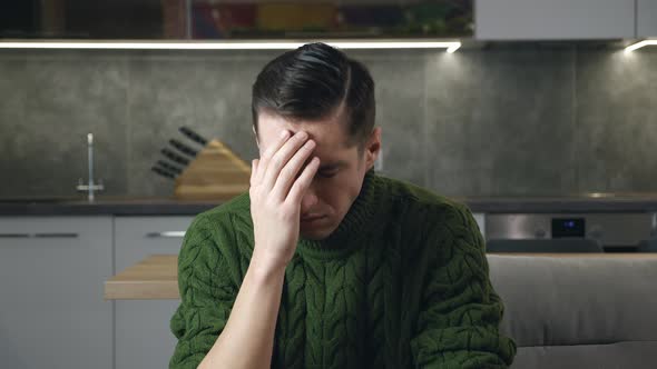 Sad Depressed Man in Despair Sitting on the Couch in Living Room