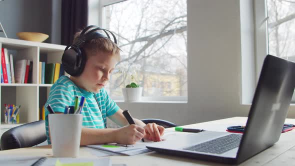 Boy is Doing  Homework at the Table. Cute Child is Learning at Home.