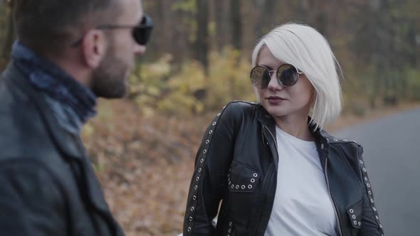 Stylish Female Biker Corrects Her Male Leather Jacket and Smiles Outdoors