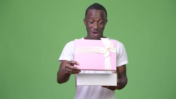 Young Happy African Man Looking Surprised While Opening Gift Box