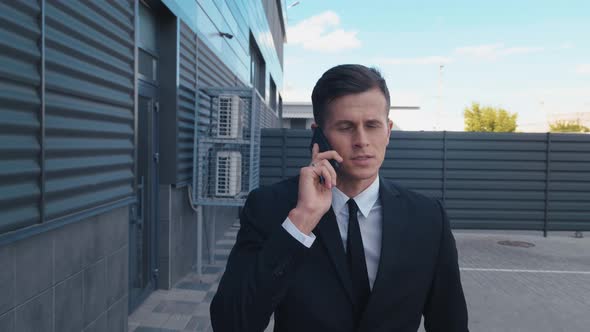 Handsome Businessman Walking on Street Near Office Center and Talking on Mobile Phone. Business