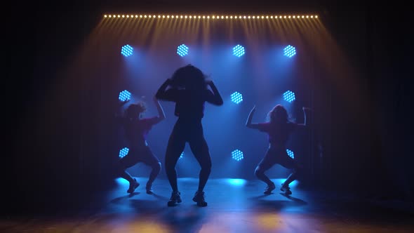 Sporty Young Girls Move in Jazz Funky Style. Silhouettes of Three Girls in a Dark Studio