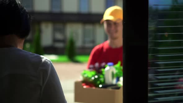 Man Courier Gives to Woman Customer Box of Fresh Food During Working Day at Delivery Service Spbd