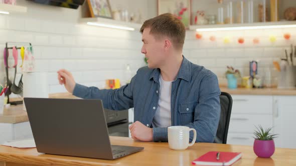 Young man communicating by conference video call speak looking at laptop at home office