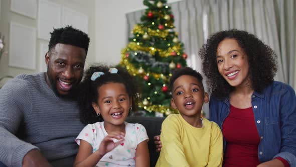 Smiling african american family having video call and gesturing, christmas decorations in background