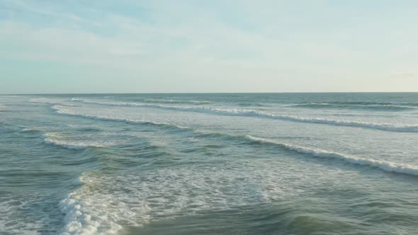 Surfer in Ocean with White Foam Waves in Afternoon Light and Clear Sky, Aerial High Angle Forward