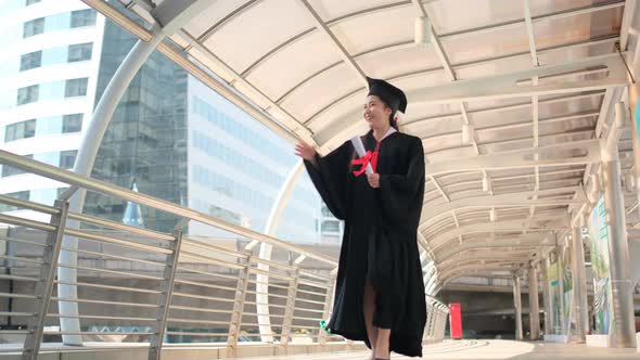 Asian beautiful women with graduation gown and hold certificate greeting together in big city