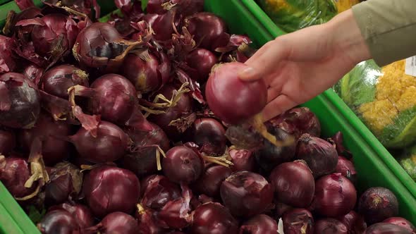 Woman Chooses Red Onions in a Supermarket