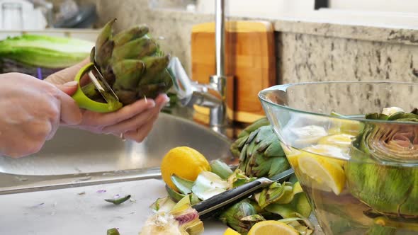 Woman Cleaning Heart of Artichokes with Spoon