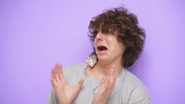 A Man with Curly Hair with a Pet Ratmouse on an Isolated Background in the Studio