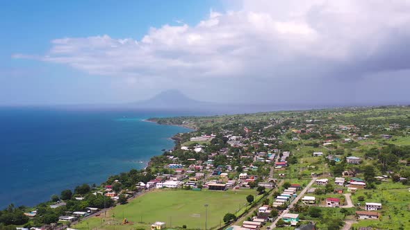 Coastal town in St. Kitts,Lesser Antilles,Caribbean below a green mountainside.