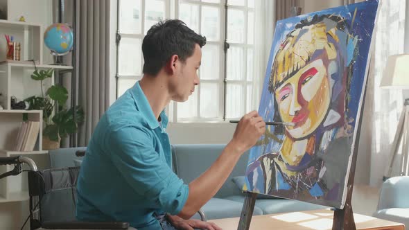 Asian Artist Man In Wheelchair Holding Paintbrush Painting A Girl On The Canvas