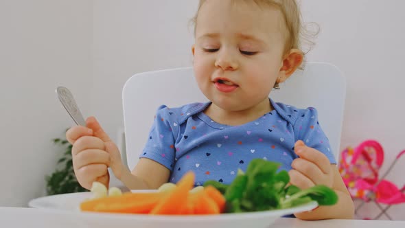 The Child Eats Pasta and Vegetables