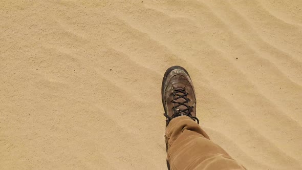 Walking through a desert, looking down at feet.