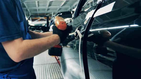 Car Factory Worker Assembling a Car Door Handle