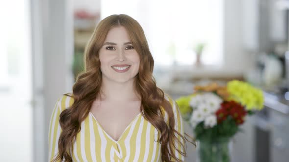 Smiling woman standing at home, looking at camera