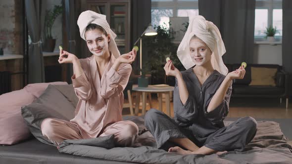 Girlfriends In Clay Masks Holding Cucumber Slices