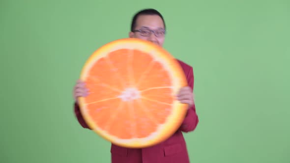 Happy Asian Businessman with Eyeglasses Holding Orange Pillow As Healthy Concept