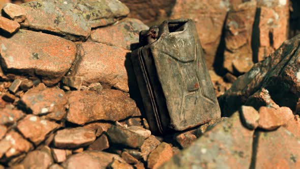 Old Rusty Metal Canister for Gasoline Fuel at Rocks alt