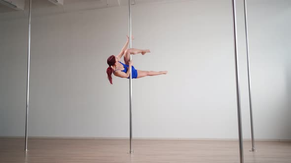 Athletic Woman Pole Dancer Performs Acrobatic Stunts with Stretching Elements