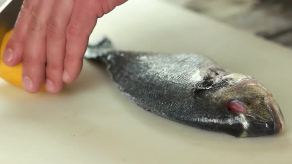 Hands Cutting Lemon, Raw Fish.