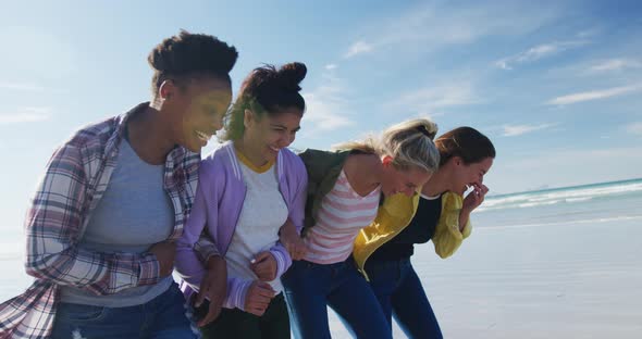 Happy group of diverse female friends having fun, walking along beach