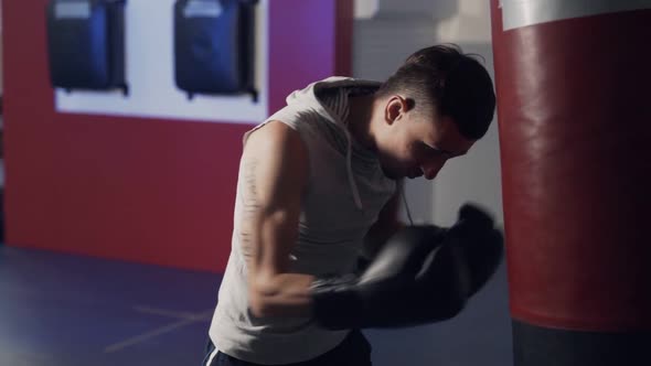 Boxer Man Working Out Blows on a Punching Bag in Slow Motion, Side View.